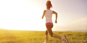 Runner athlete running on sunrise/sunset grass field